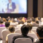 Personnes de dos regardant la scène d'un congrès