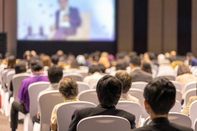 Personnes de dos regardant la scène d'un congrès
